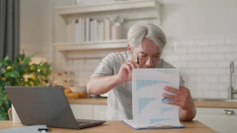 Senior man in home office at kitchen table reviewing paperwork and document.. Stock Footage 332748707
