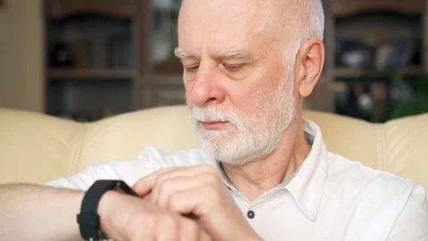 Senior man at home using smartwatch, browsing, reading news. Concept of Stock Footage 87040333