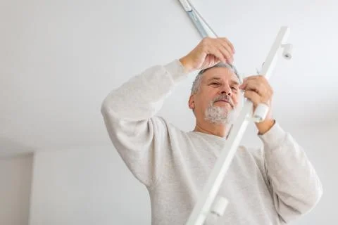 Senior man installing a ceiling light Stock-Fotos