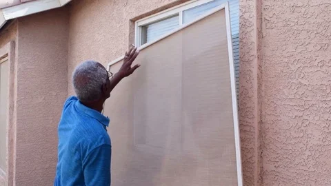 A senior man installing a window screen on house Video stock 93522184