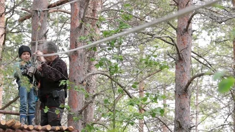 Senior man is instructing and helping little girl to set equipment on zipline Stock Footage 80821657