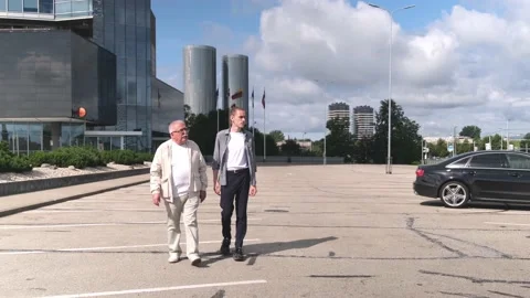 Senior man in jacket and guy walk along parking lot in city Stock Footage 139797795
