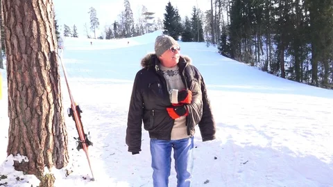 Senior man in jacket stands and warms up against ski slope Stock Footage 109192568