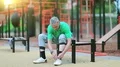 Senior man laces up his jogging shoes near sports ground HD Footage