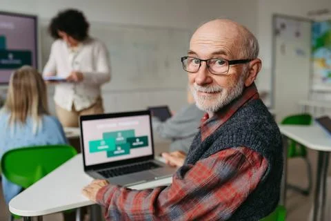 Senior man learning digital skills with tutor support in community center. 库存照片