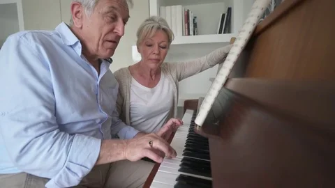 Senior man learning how to play piano with teacher Stock Footage