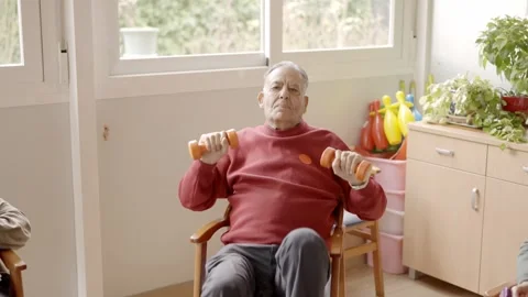 Senior man lifting dumbbells with difficulty in a nursing home Stock Footage 274429389