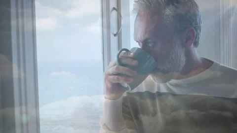 Senior man lifting teal mug sipping musing turning as moving cloud overlay Stock Footage 333351639
