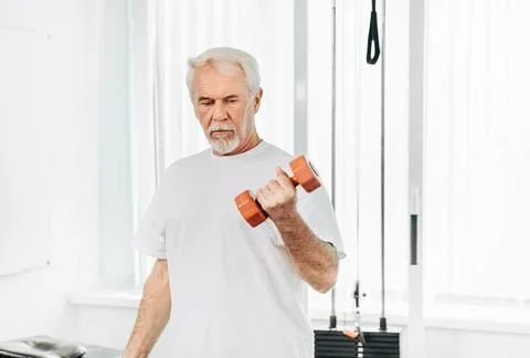 Senior man lifting weights at an exercise class. healthy lifestyle old people Stock Photos