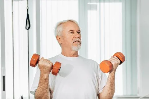 Senior man lifting weights at an exercise class. healthy lifestyle old people Stock Photos