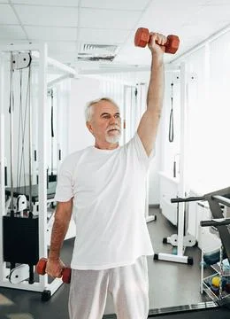 Senior man lifting weights at an exercise class. healthy lifestyle old people Stock Photos