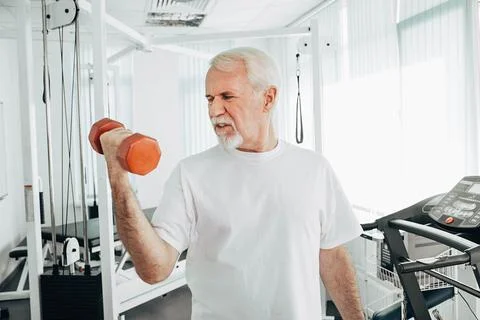 Senior man lifting weights at an exercise class. healthy lifestyle old people Stock Photos