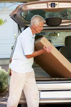 Senior Man Loading Large Package Into Back Of Car Stockfoto's