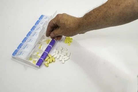 A senior man loading a weekly pill organizer. Stock Photos