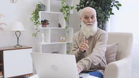 Senior man with long beard talks on video call with colleague via laptop Stock Footage 225103110