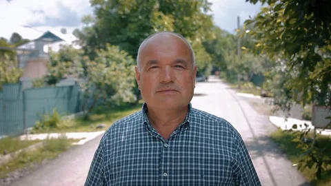 Senior man looking at camera, small street, outdoor portrait Stock Footage 127786272
