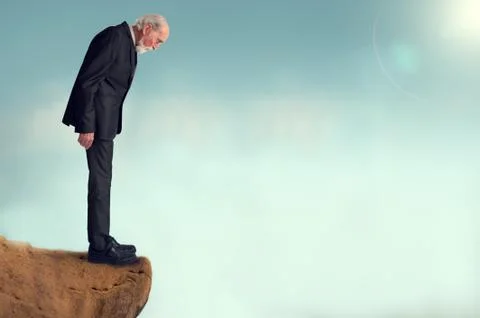 Senior man looking down from a cliff Stock Photos
