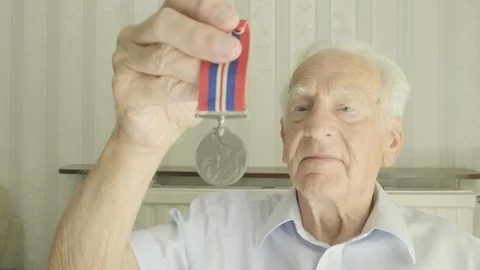 Senior man looking at an old medal Video stock 113070448