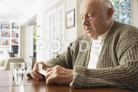 Senior Man Looking At Pill Organizer