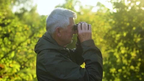 Senior man looking through binoculars in nature. Copy space. Video stock 138499954