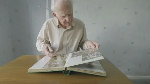 Senior man looking through an old photo album Video stock 104584864