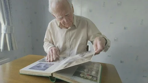 Senior man looking through an old photo album Video stock 104585387