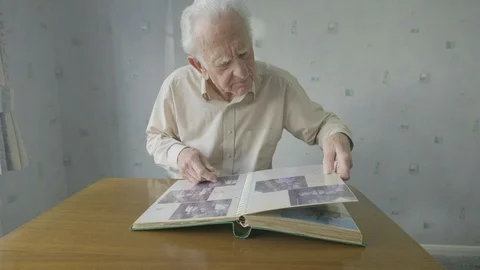 Senior man looking through an old photo album Video stock 104586424