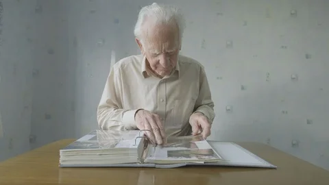 Senior man looking through an old photo album Video stock 104588056