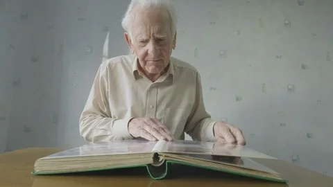 Senior man looking through an old photo album Video stock 104588663