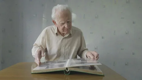 Senior man looking through an old photo album Video stock 104590803