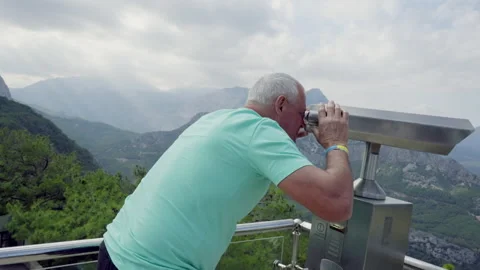 Senior man looking through a telescope at the mountain view Stock Footage 203960377