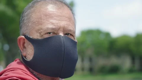 Senior man looking towards camera with sad look, wearing protective face mask Stock Footage 131058355