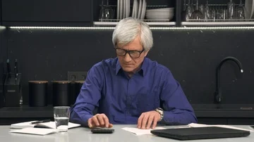 Senior man looks at documents and considers on calculator Stock Footage 85882554