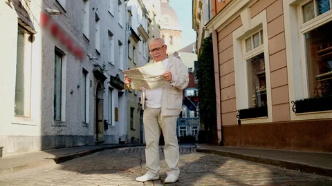 Senior man looks at map on paved street in beautiful city Stock Footage 115883926