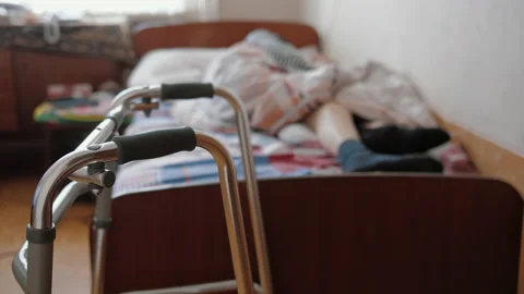 Senior man lying, resting on bed, zimmer frame for walk stand in front of Stock Footage 165734522