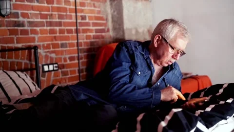 Senior man lying with smartphone on bed at home Stock Footage 104654411