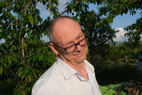 Senior man making funny faces and peeking over glasses at camera near apple Foto stock