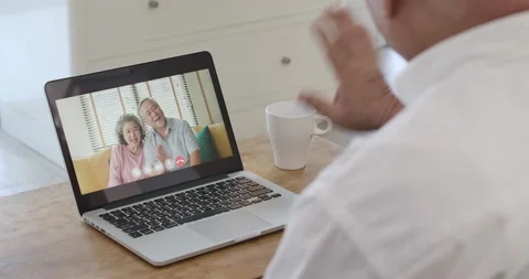 Senior man making video call to friends with laptop at home. Video stock 153250290