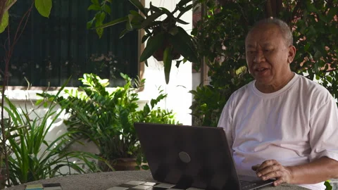 Senior man making a video call in the garden Stock Footage 253146953