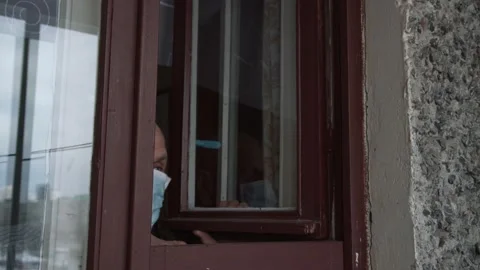 Senior man opens brown obsolete window and head appears Stock Footage 157357266