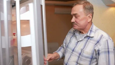 Senior man opens the fridge and drink the juice from the package. It quenches Stock Footage 70134183