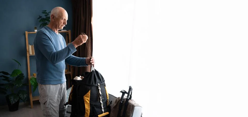 Senior Man packing backpack with different camping equipment at home. Copy space Stock Photos