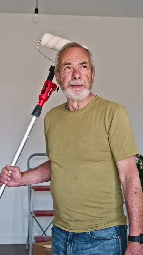 Senior man with paint roller moving into new home Stock Footage 345821771