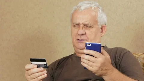 Senior man pay for purchases in the Internet bank credit card. He carefully Stock Footage 71244262