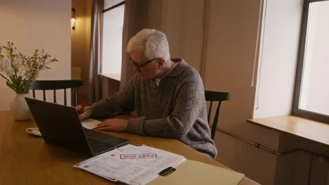 Senior Man Paying Overdue Bills Online Using Laptop at Home Vídeo Stock 330389864