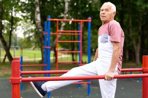 Senior man performing parallel bar exercises in park Stock Photos