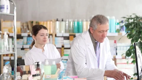 Senior man pharmacist use computer, girl intern with prescription Stock Footage 335615221