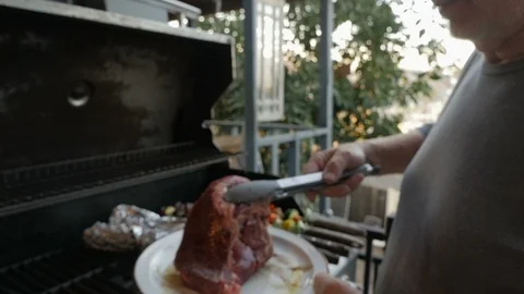 Senior man placing a red steak on a hot bbq grill with vegetable kebabs Stock Footage 86002405