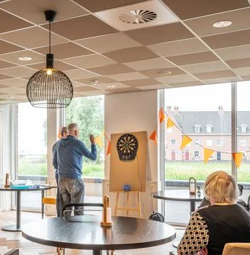 Senior man playing darts, while other seniors are watching Stock Photos