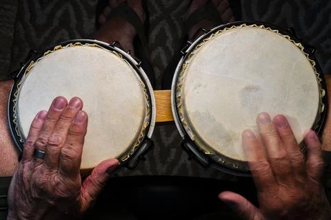 Senior man playing a set of bongo drums 24.07.2024 Stock Photos